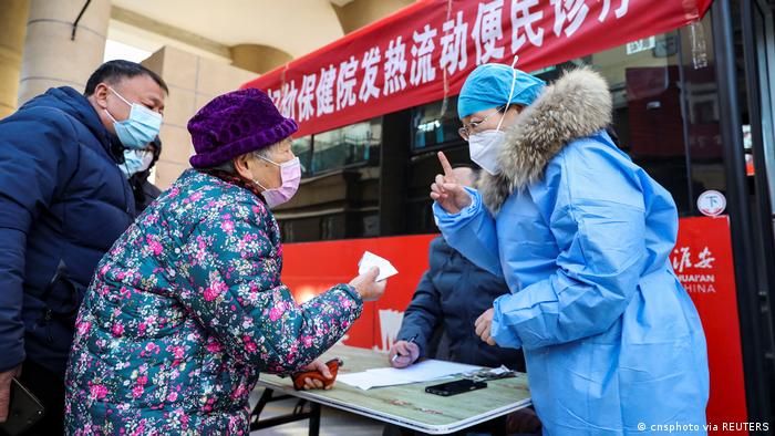 12月25日江苏一名医务人员在由巴士改装的移动发烧诊所前，向居民提供照护指导 ...