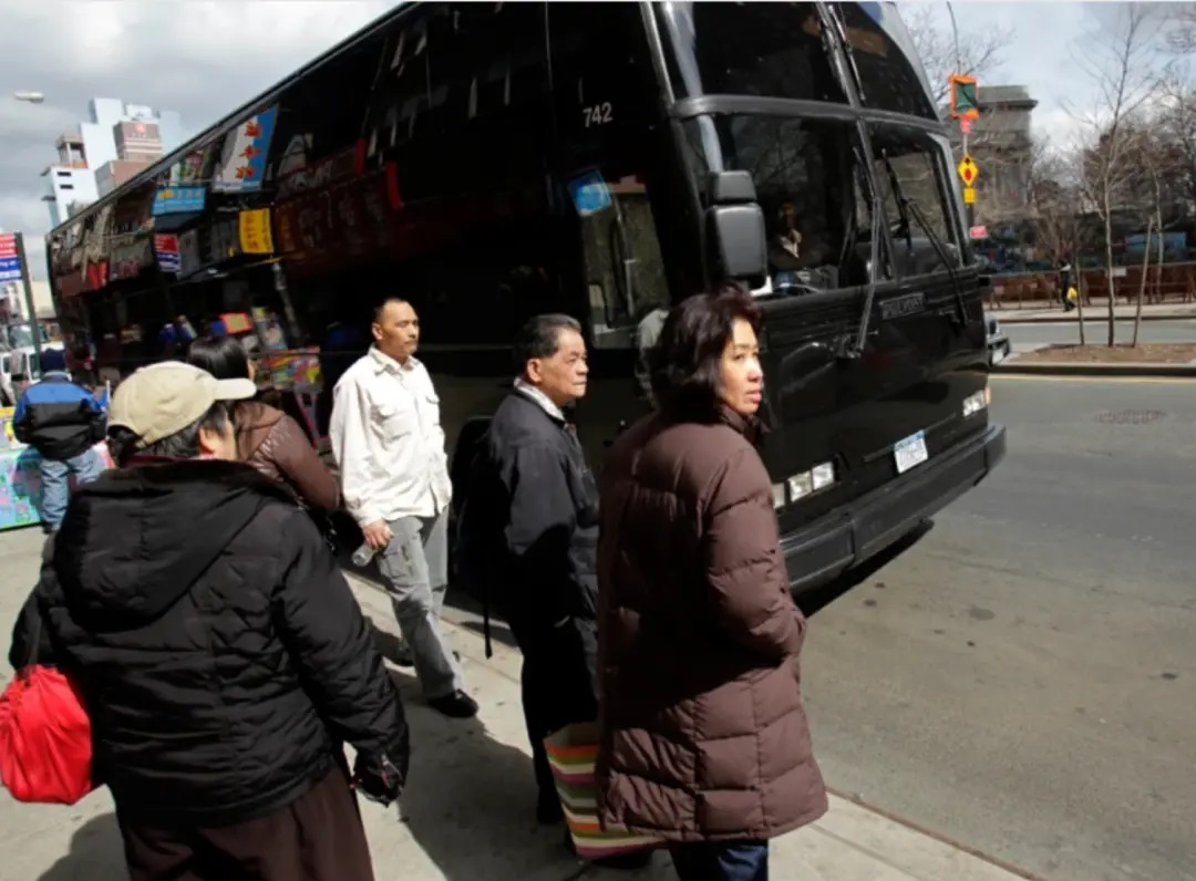 纽约的清早，一些老年华裔移民收拾妥当，拎着保温饭盒前往唐人街的站点、等待他们的大巴车 ...
